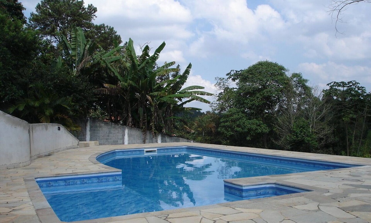 Suzano House | House on a farm with a fireplace and a lake within the property.