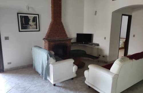 Suzano House | House on a farm with a fireplace and a lake within the property.