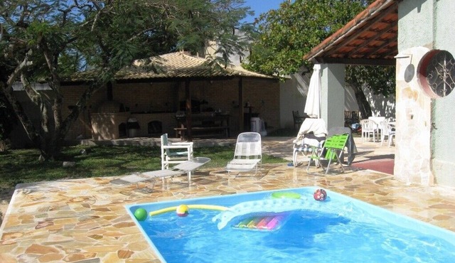 House surrounded by a veranda, swimming pool, barbecue area, and volleyball/beach tennis court.